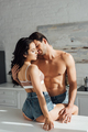 Hot woman with closed eyes on table hugging with man in kitchen - PhotoDune Item for Sale