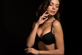 attractive, sexy girl in black bra touching face while posing isolated on black - PhotoDune Item for Sale