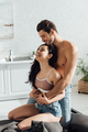 Man hugging attractive happy woman from behind  on sofa in kitchen - PhotoDune Item for Sale