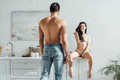 Man in front of hot girl sitting on kitchen cabinet and smiling - PhotoDune Item for Sale