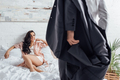 Selective focus of businessman taking off blazer in front of woman on bed in bedroom - PhotoDune Item for Sale