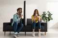 Man sitting near model of smartphone and addicted girlfriend chatting on couch - PhotoDune Item for Sale