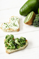 selective focus of heart shaped canape with creamy cheese, broccoli, microgreen near green fruits - PhotoDune Item for Sale