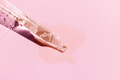 Close up of a pipette with pouring liquid serum on pink background - PhotoDune Item for Sale