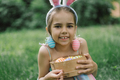 Girl with eggs basket and bunny ears on Easter egg hunt in garden. - PhotoDune Item for Sale