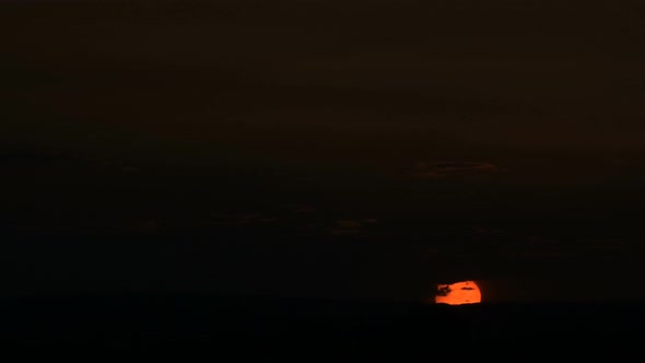 Timelapse of the Setting Sun Behind the Clouds at Sunset Over the Small Town. Swirling Clouds Before