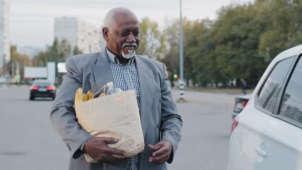 Old African American Man Gray Hair Beard Carries Bag of Groceries in Hand Carefree Male Opens