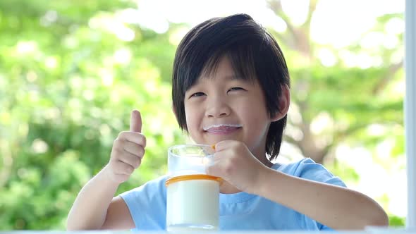 Cute Asian Child With A Glass Of Milk Showing Thumb