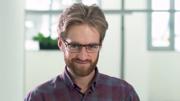Portrait a Smiling Bearded Guy with Glasses in a Daily Plaid Shirt Standing in the Office Center
