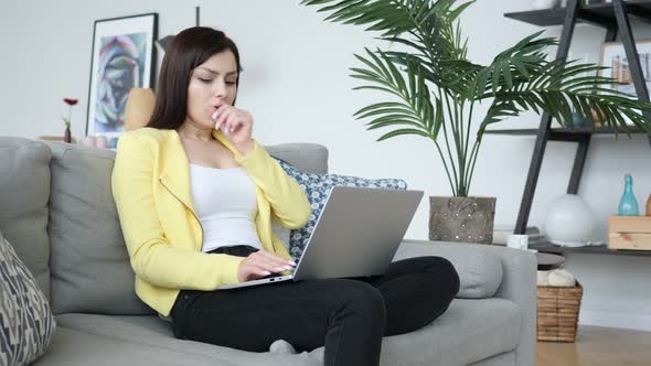 Sick Creative Woman Coughing while Sitting on Sofa and Typing on Laptop