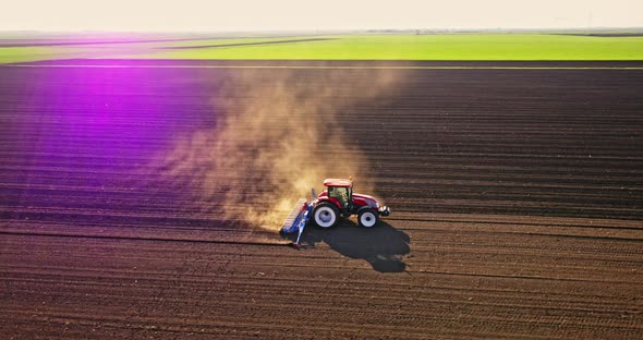 Farmer seeding soybeans with tractor on plowed field