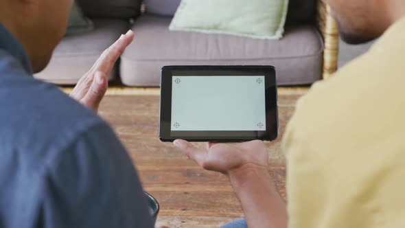 Father and son waving hands during video call on digital tablet with blank screen and copy space