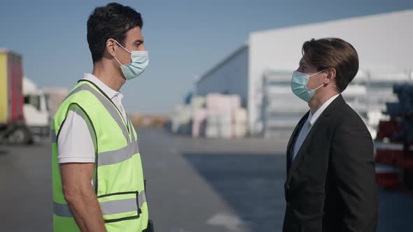 Side View of Caucasian and Middle Eastern Men in Covid19 Face Masks Talking Turning Looking at