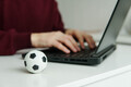 A man reading football news on laptop. Soccer ball on the table. Betting, gambling concept. - PhotoDune Item for Sale