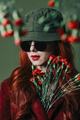 Stylish redhead woman in hat and burgundy color suit with carnations on green background - PhotoDune Item for Sale