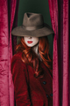 Stylish redhead woman in hat peek through the viva magenta color curtains - PhotoDune Item for Sale