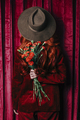 Stylish redhead woman in hat with carnations peek through the viva magenta color curtains - PhotoDune Item for Sale