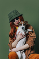 Stylish redhead woman with headphones and dog on green background - PhotoDune Item for Sale
