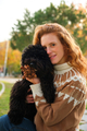 Young woman hugging her black puppy poodle dog in a park. - PhotoDune Item for Sale