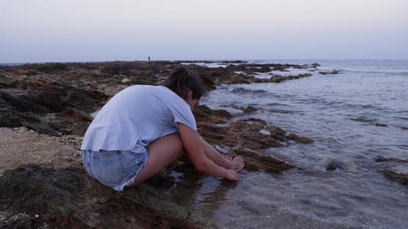 Teenage girl sitting on cliff by the sea