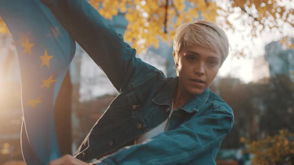 Young Blond Woman Spinning in the Park with the European Union Flag