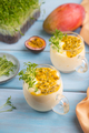 Mango yogurt with passionfruit and cilantro microgreen in glass on blue. Side view, selective focus. - PhotoDune Item for Sale