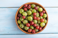 Fresh red and green gooseberry in wooden bowl on blue wooden, top view. - PhotoDune Item for Sale