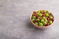 Fresh red and green gooseberry in ceramic bowl on gray concrete, side view, copy space. - PhotoDune Item for Sale