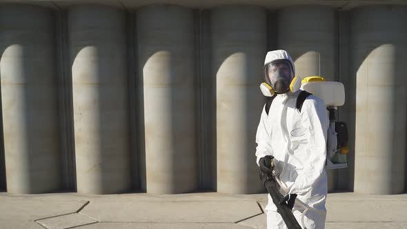 Cleaner with Pressurized Sprayer in Hands Going To Disinfect Public Places