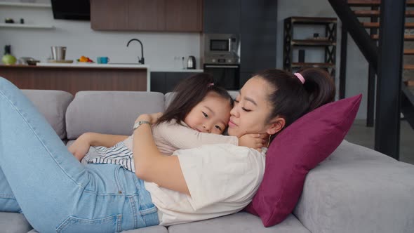 Happy Asian Mom and Toddler Girl in Love Embrace Indoors