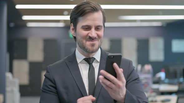 Portrait of Businessman Celebrating on Smartphone