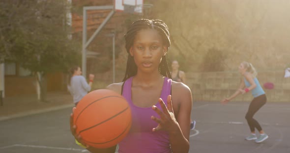 Portrait of african american female basketball player holding ball and looking at camera