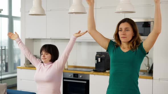 Portrait of Mature Woman with Handicapped Daughter Practicing Yoga at Home