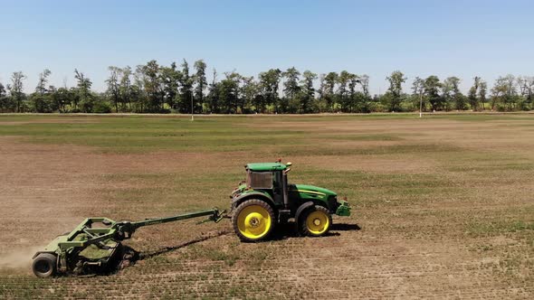 Aerial View of a Tractor with a Mower Mows the Grass on an Empty Field