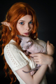 Portrait of young woman cosplayer elf in white knitted dress hugging Sphinx kitten. Black background - PhotoDune Item for Sale