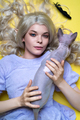 Young female cosplay elf in blue dress looking at camera lying down with cat on yellow background - PhotoDune Item for Sale