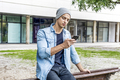 Attractive young smiling man using phone in a public park - PhotoDune Item for Sale