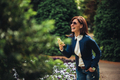 A woman laughing and holding her phone, walking through the park. - PhotoDune Item for Sale