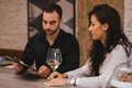 Man and woman having a business meeting at the restaurant, drinking wine, reading some documents. - PhotoDune Item for Sale