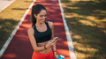 Smiling fitness girl, finished her training, using a mobile phone. - PhotoDune Item for Sale