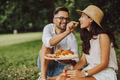 Smiling man having a picnic with his girlfriend, giving her a peace of cheese. - PhotoDune Item for Sale