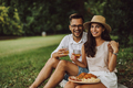 Portrait of two smiling lovers, sitting next to each other, having a picnic outdoor. - PhotoDune Item for Sale