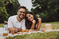 Portrait of two lovers, smiling for the camera, enjoying their picnic. - PhotoDune Item for Sale