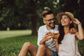 Positive couple enjoying their picnic outdoor, sitting on the grass, drinking a beer. - PhotoDune Item for Sale