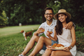 Portrait of two lovers, sitting down, spending time in the park, holding a board with food on it. - PhotoDune Item for Sale