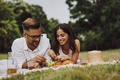 Beautiful couple laying on the grass, eating grapes, enjoying the nature. - PhotoDune Item for Sale