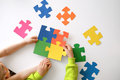 A large puzzle of colorful parts in the hands of a child. - PhotoDune Item for Sale