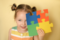 Kid cheerfully while closing eye holding puzzle of colorful details in hand - PhotoDune Item for Sale