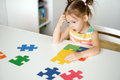 A preschooler sits thoughtfully at table in nursery, solving a puzzle - PhotoDune Item for Sale