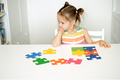 Sad, brooding girl with autism is sitting at desk solving puzzle - PhotoDune Item for Sale